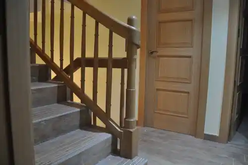 Barandilla de madera con pasamanos envolvente sobre pilastra