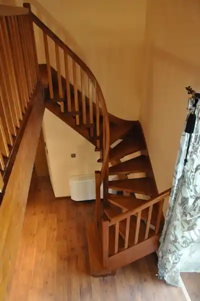 Escalera madera con barandilla curva y peldaños compensados