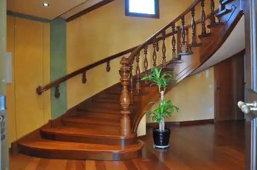 Escalera madera clásica con balaustres torneados y pasamanos curvo