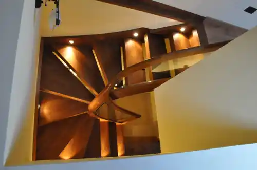 Escalera madera con barandilla de cristal y luces indirectas